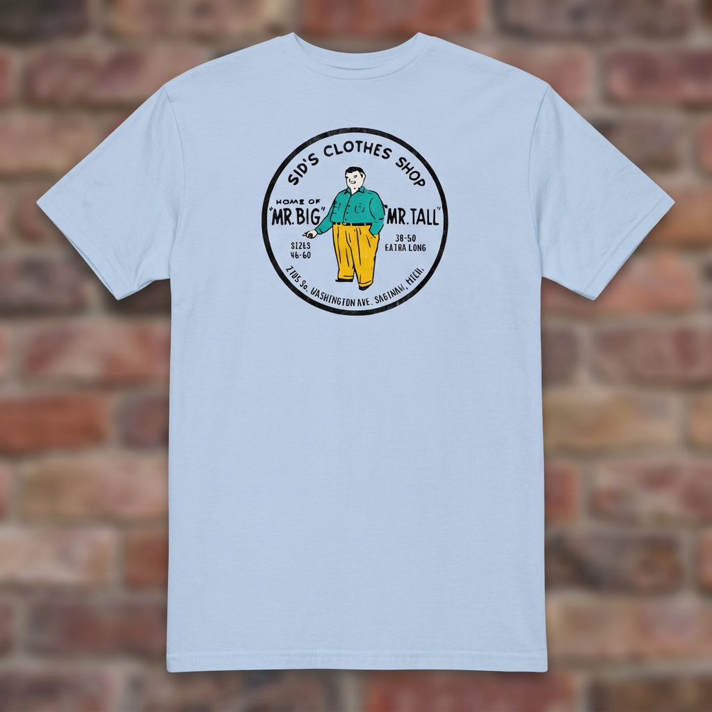 Sid's Clothing Shop Saginaw T-shirt in Light Blue, flat lay on warm brick background