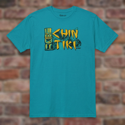 Chin Tiki Tropical Blue T-shirt flat lay on brick background