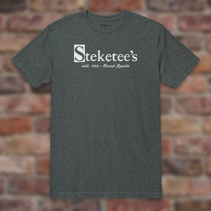 Steketee's Dark Heather T-shirt flat lay on brick background