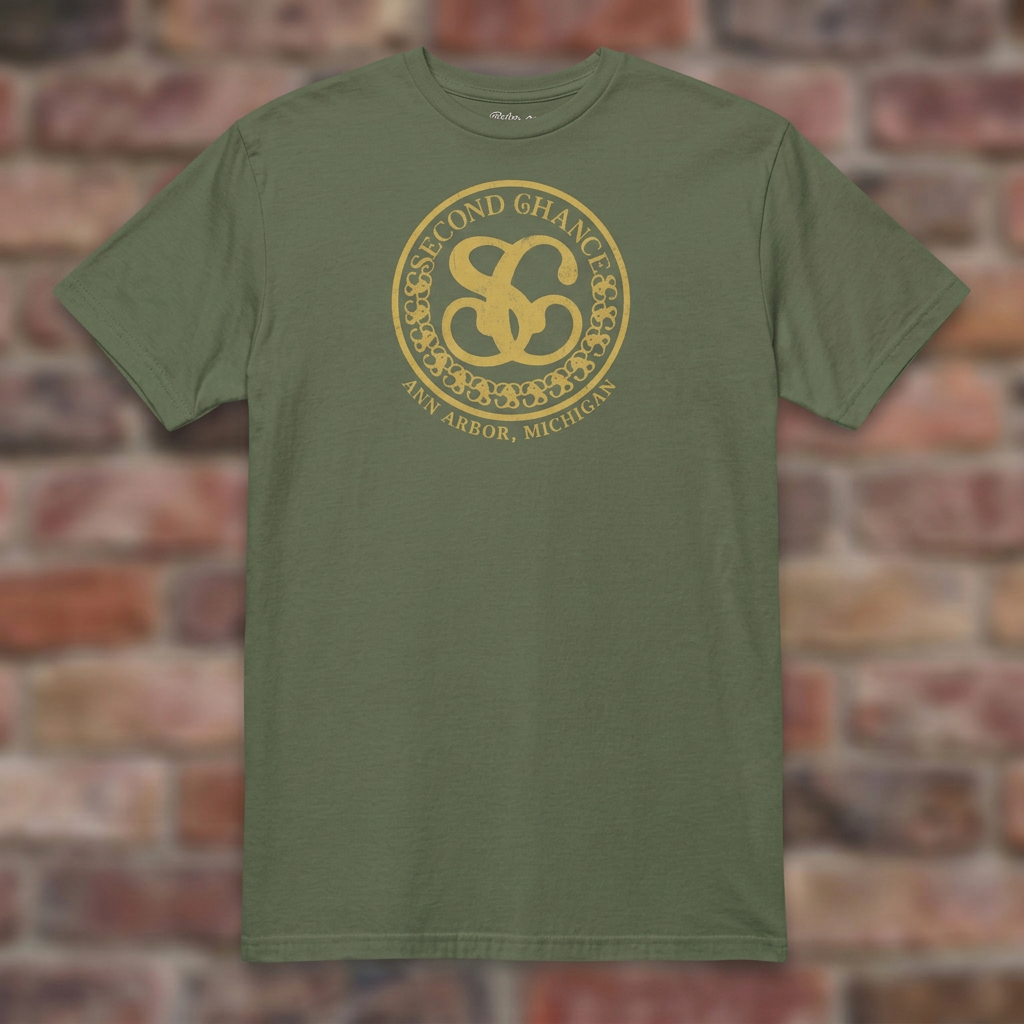 Second Chance Military Green T-shirt flat lay on brick background