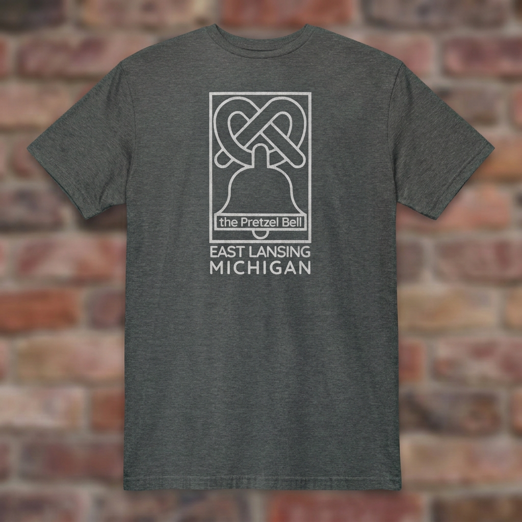 The Pretzel Bell East Lansing Dark Heather T-shirt flat lay on brick background