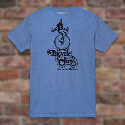 Bicycle Jim's Heather Royal T-shirt flat lay on brick background