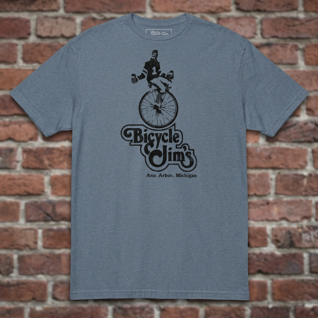 Bicycle Jim's Heather Indigo T-shirt flat lay on brick background