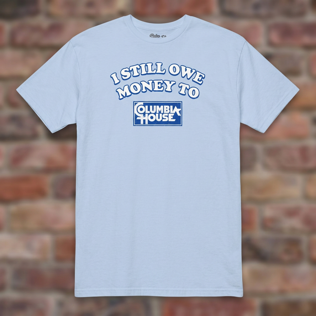 I Still Owe Money To Columbia House Light Blue T-shirt flat lay on brick background