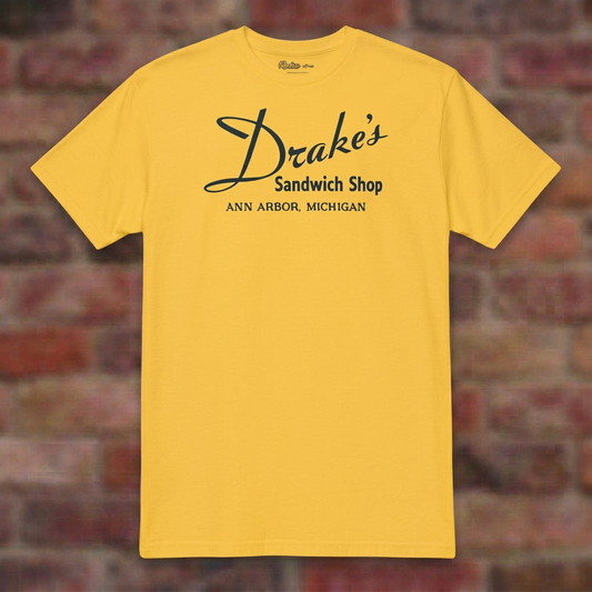 Drake's Sandwich Shop Daisy T-shirt flat lay on brick background
