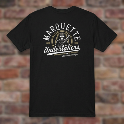 Marquette Undertakers Black T-shirt flat lay on brick background