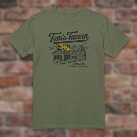 Military Green Tom’s Tavern T-shirt flat lay on warm brick