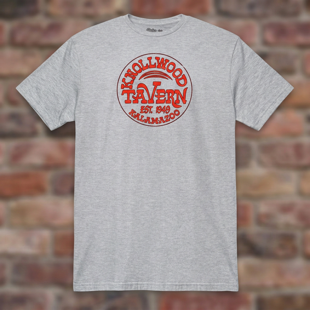Sport Grey Knollwood Tavern Kalamazoo T-shirt flat-lay against weathered brick