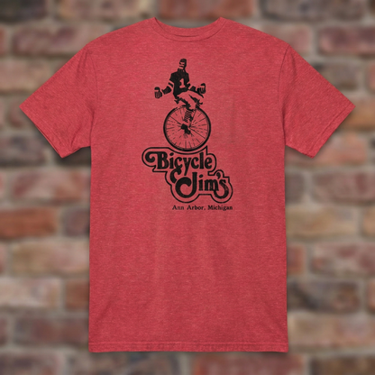 Bicycle Jim's Heather Red T-shirt flat lay on brick background