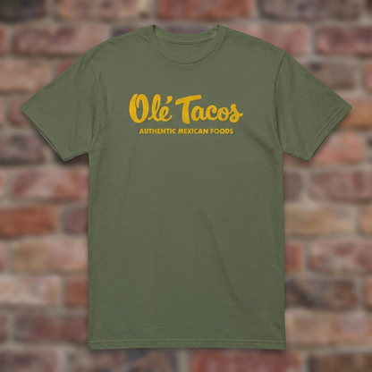 Ole Tacos Military Green T-shirt flat lay on brick background