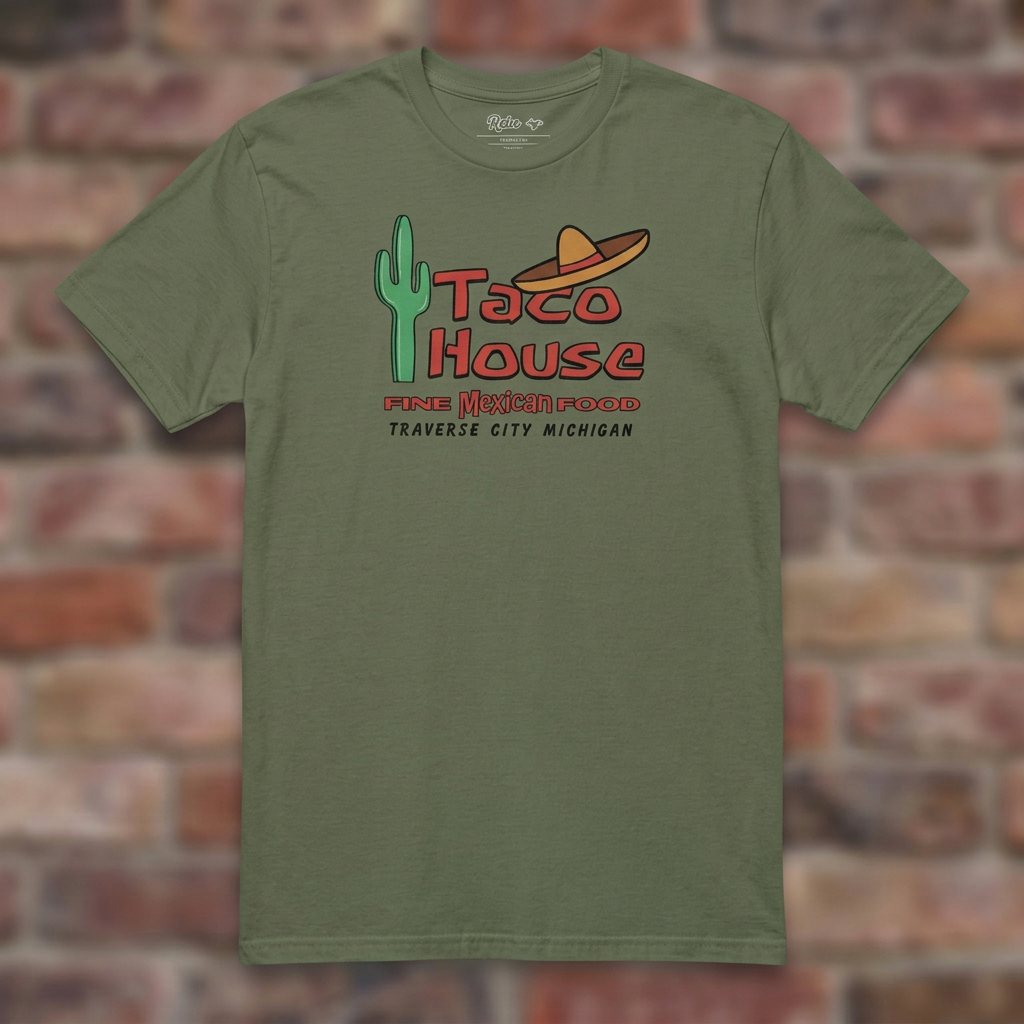 Taco House Traverse City Military Green T-shirt flat lay on brick background