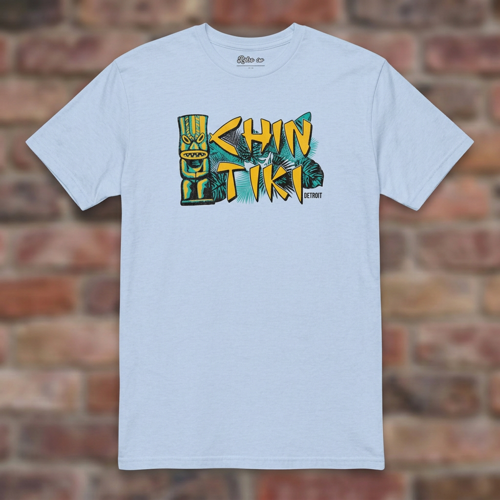 Chin Tiki Light Blue T-shirt flat lay on brick background