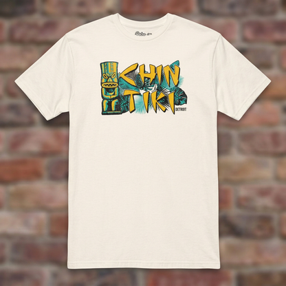 Chin Tiki Natural T-shirt flat lay on brick background