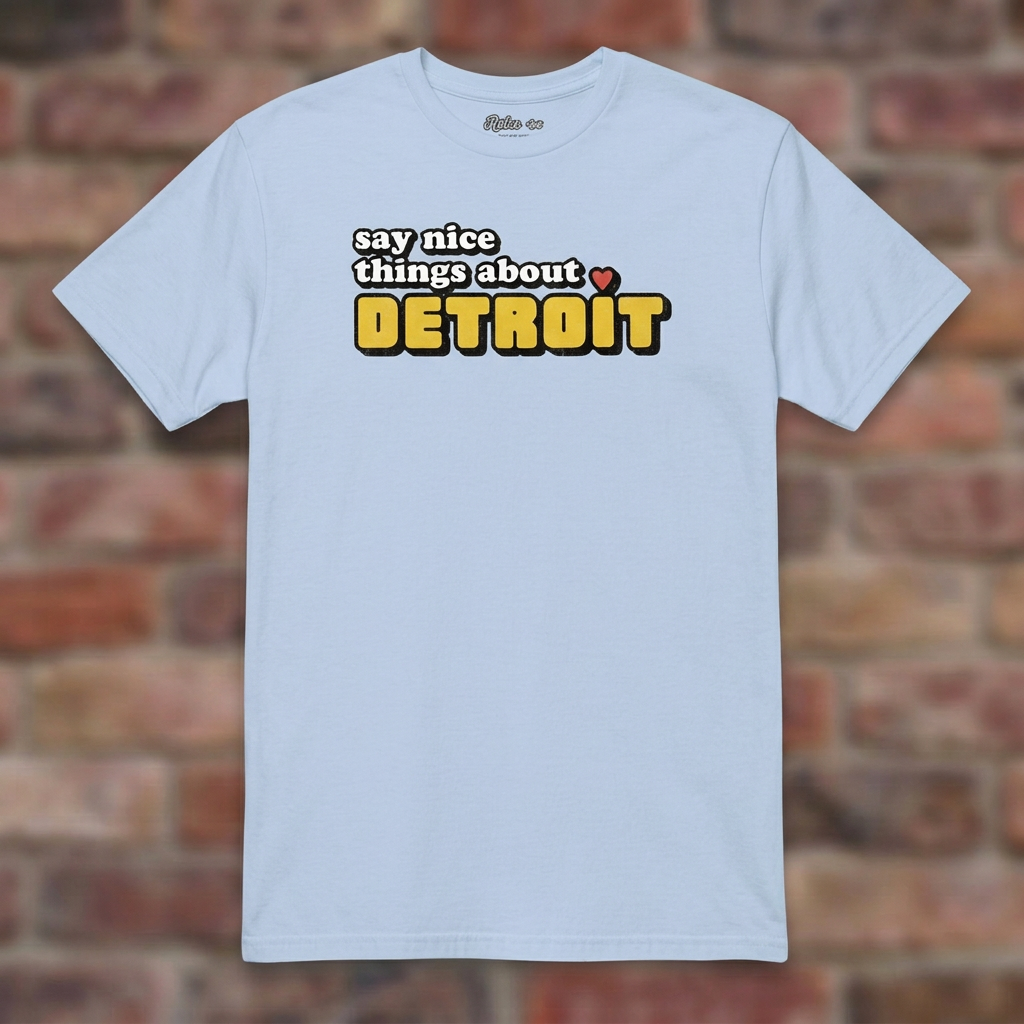 Say Nice Things About Detroit Light Blue T-shirt flat lay on brick background