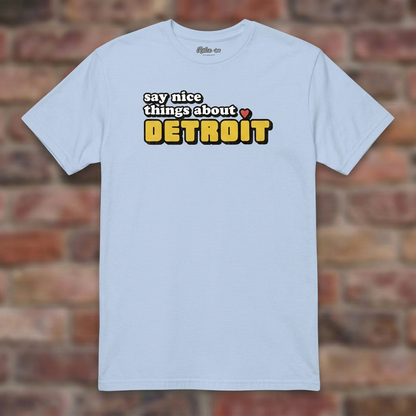 Say Nice Things About Detroit Light Blue T-shirt flat lay on brick background