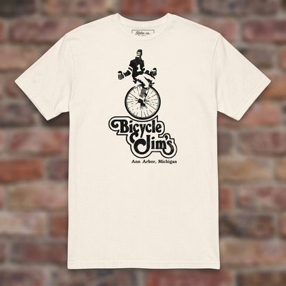 Bicycle Jim's Natural T-shirt flat lay on brick background