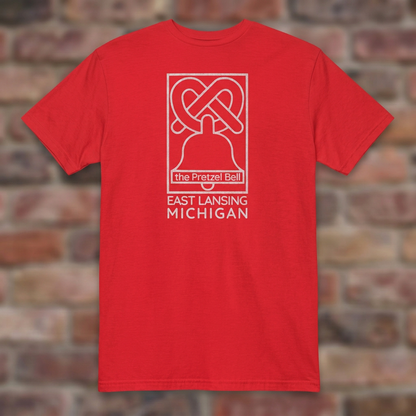 The Pretzel Bell East Lansing Red T-shirt flat lay on brick background