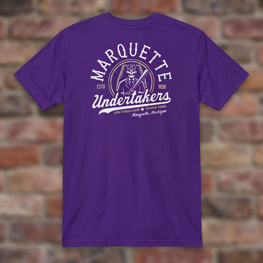 Marquette Undertakers Purple T-shirt flat lay on brick background