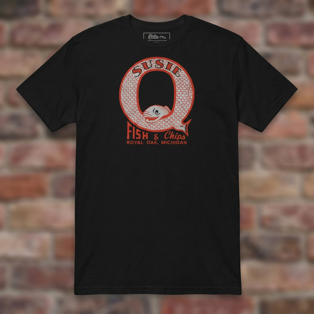 Susie Q Fish-n-Chips Black T-shirt flat lay on brick background