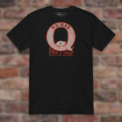 Susie Q Fish-n-Chips Black T-shirt flat lay on brick background
