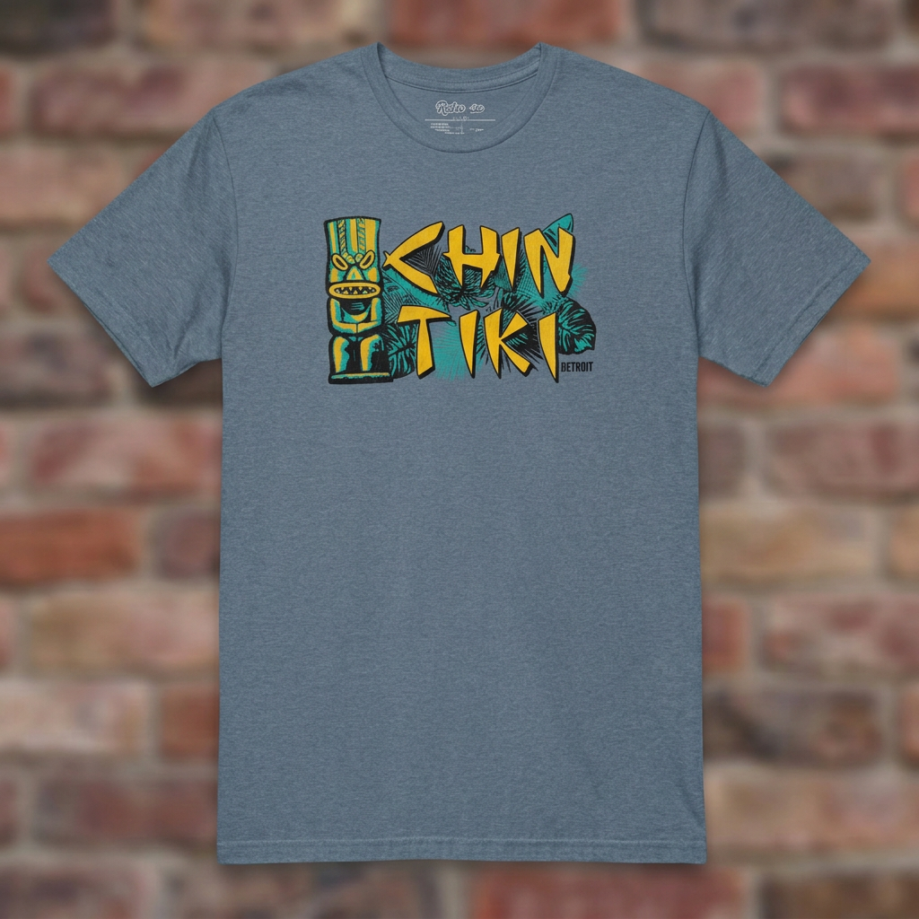 Chin Tiki Heather Indigo T-shirt flat lay on brick background