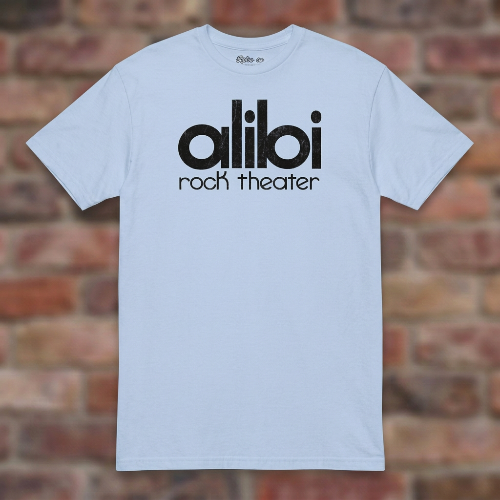 Alibi Rock Theater Light Blue T-shirt flat lay on brick background
