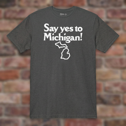 Say yes to Michigan Dark Heather Grey T-shirt flat lay on brick background