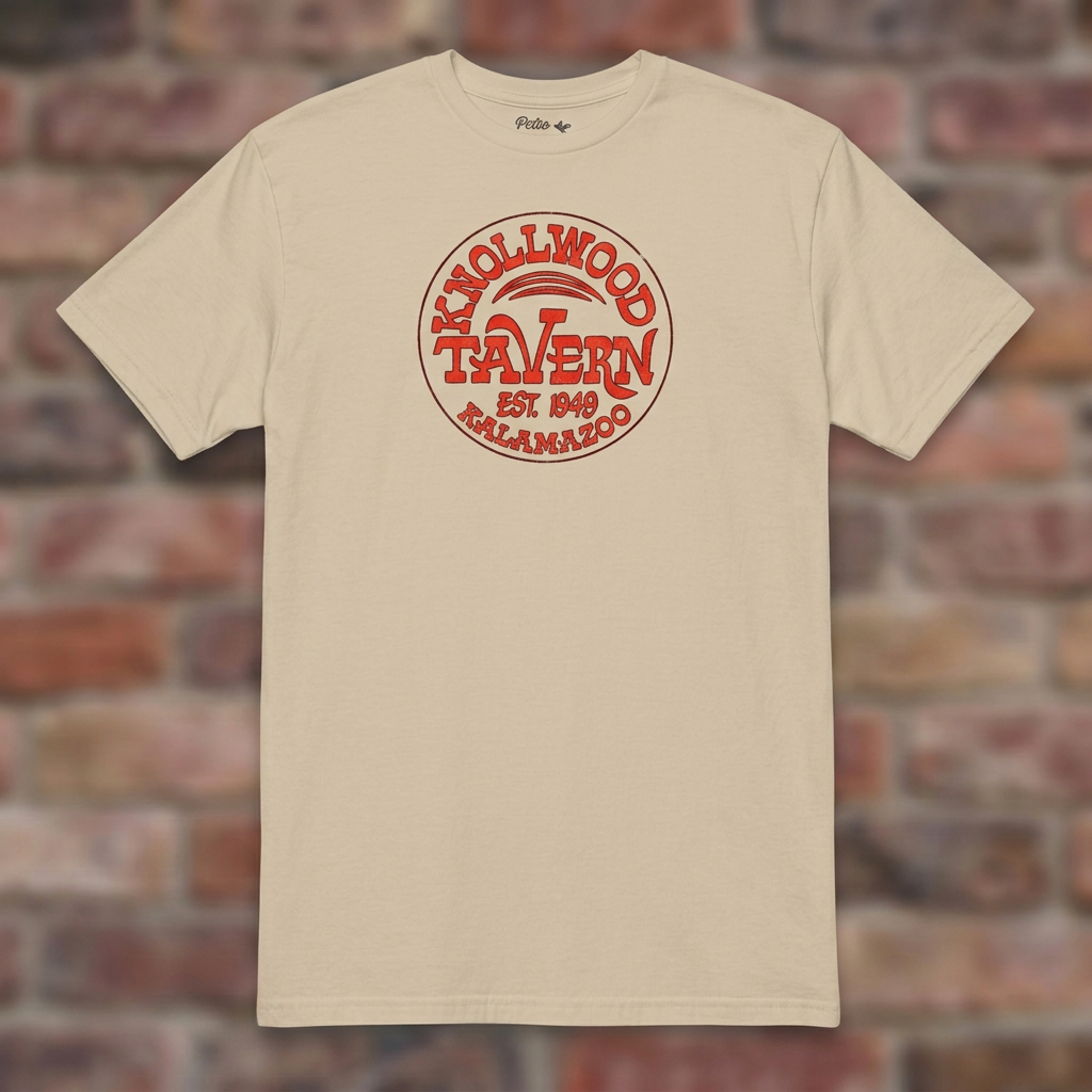 Sand Knollwood Tavern Kalamazoo T-shirt flat-lay against weathered brick