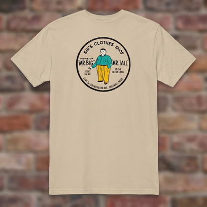 Sid's Clothing Shop Saginaw T-shirt in Sand, flat lay on warm brick background