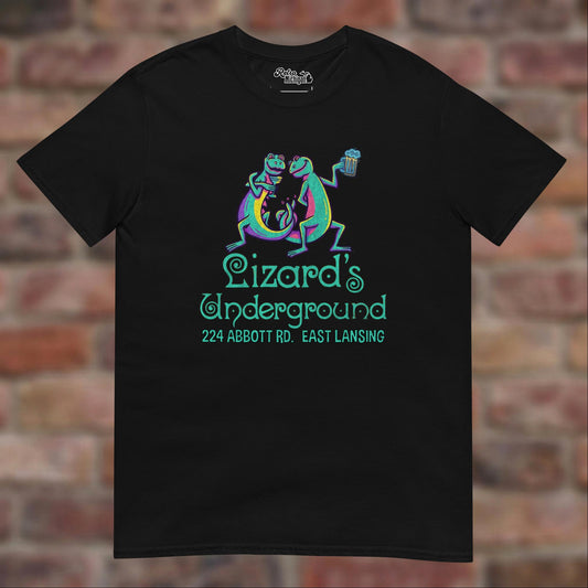 Lizard's Underground East Lansing Black T-shirt flat lay on brick background